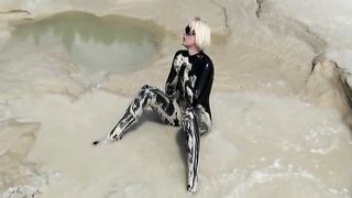 Super Hot Blond Girl in Black Latex Catsuit + High Heels and Sunglasses Bathes in the Mud - Mud Bath