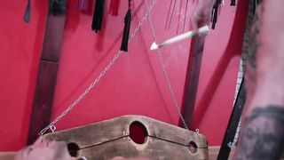 Dominatrix Nika pours hot wax from a candle on a slave